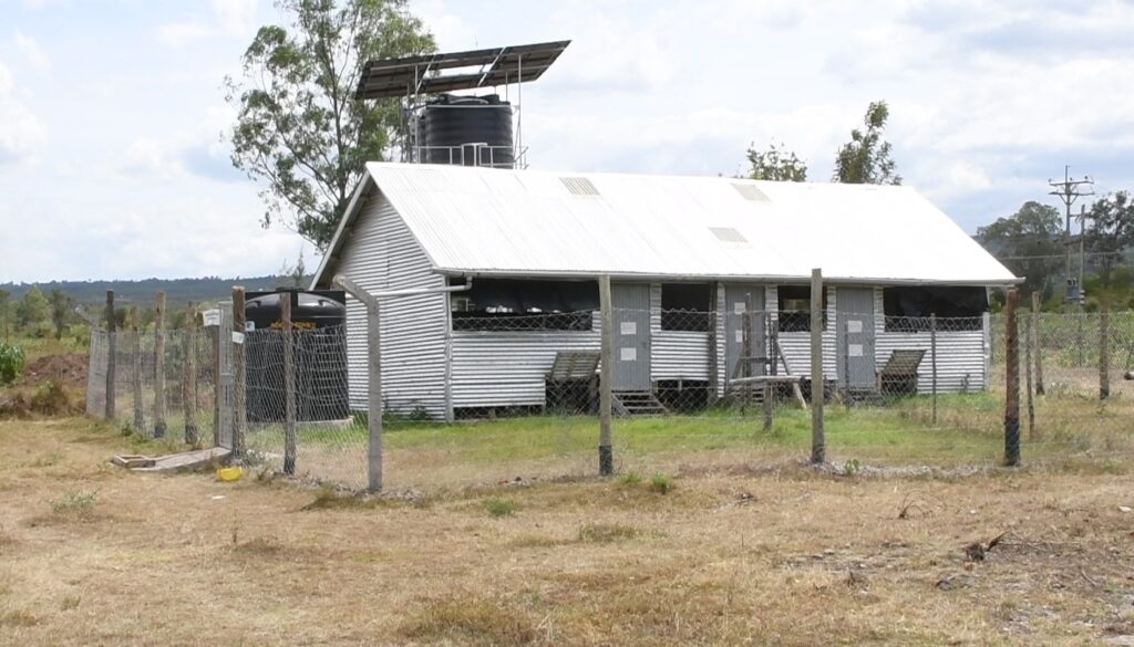 A poultry house at the farm with a water tower seen in the background